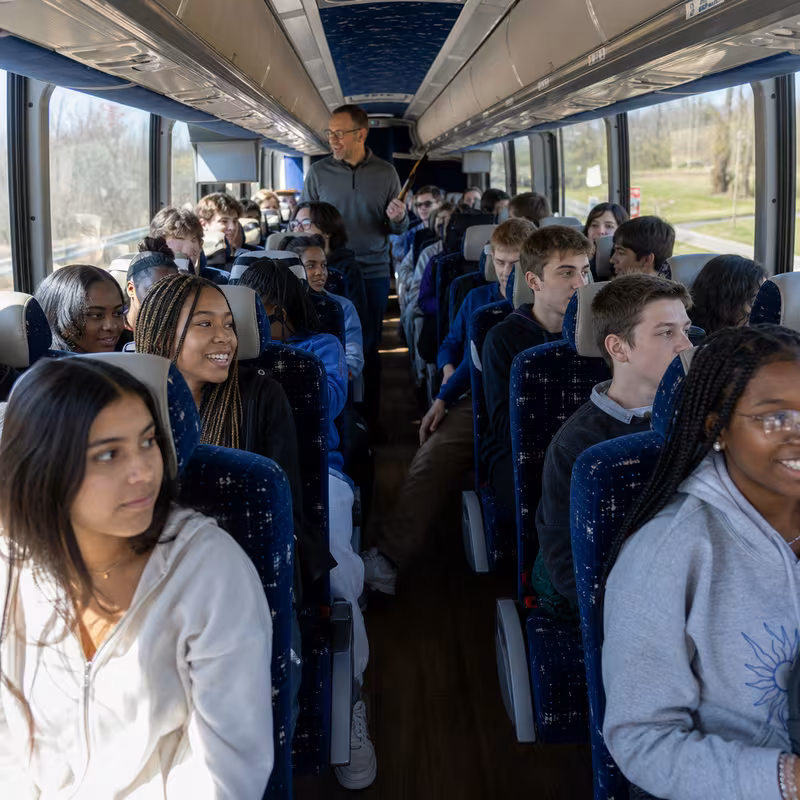 Group boarding a white charter bus for School Transportation transportation in Tucson