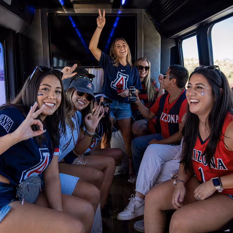 Group boarding a white charter bus for Sporting Event Transportation transportation in Tucson
